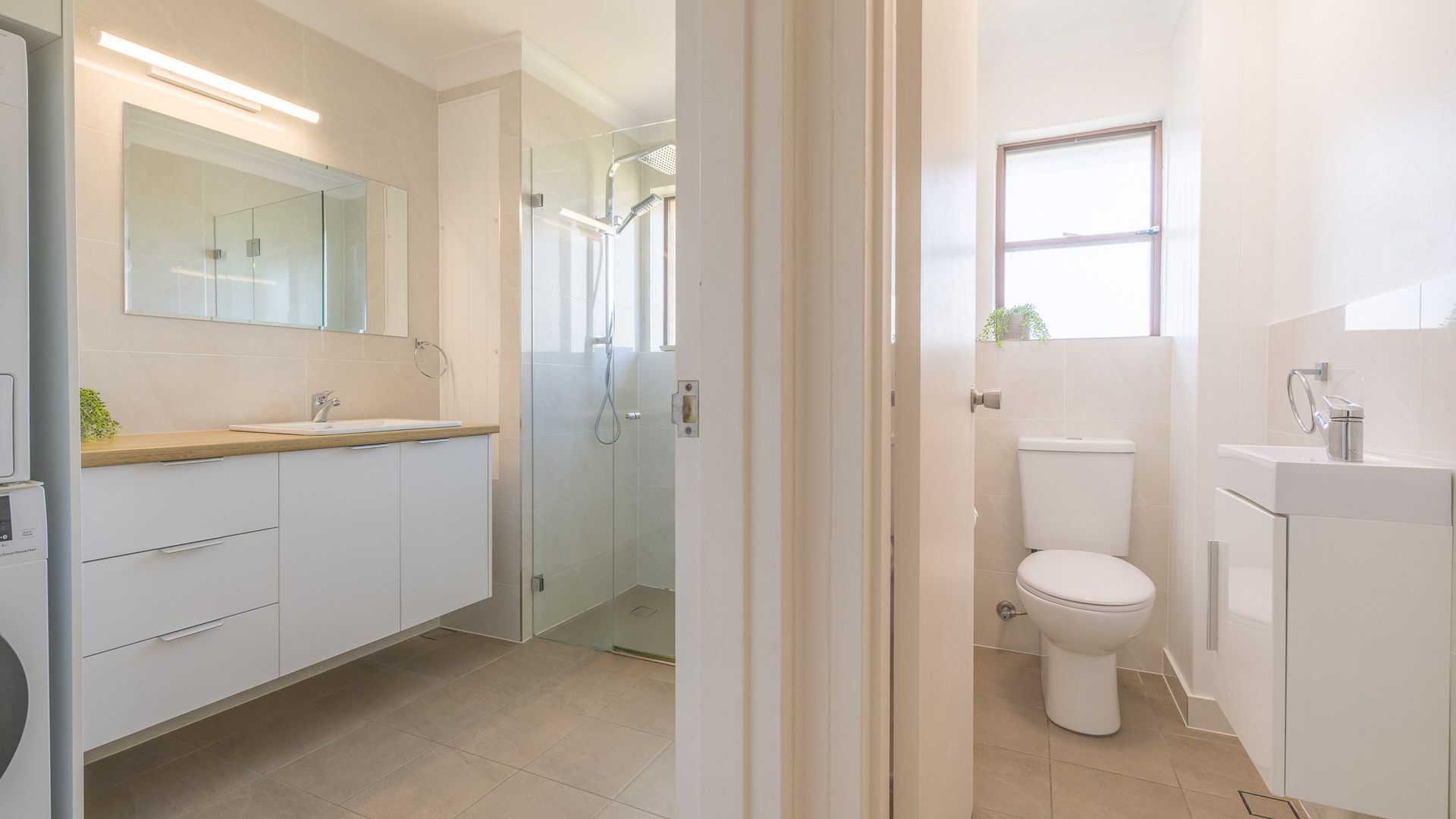 A modern bathroom with a glass shower enclosure, a toilet, and a sink with a mirror above it.