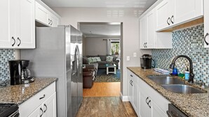 A modern kitchen with white cabinets, granite countertops, and stainless steel appliances.