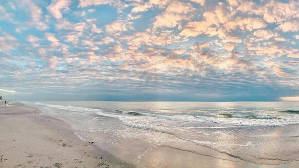 A beach with a wide sandy shore and gentle waves.