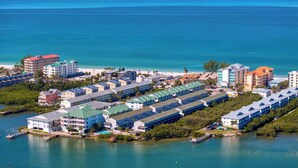 An aerial view of a coastal hotel area with multiple buildings, a marina, and a beach.