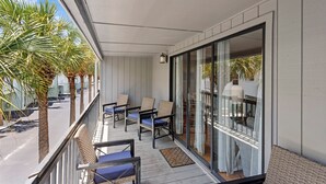 A balcony with wicker chairs and a view of palm trees.