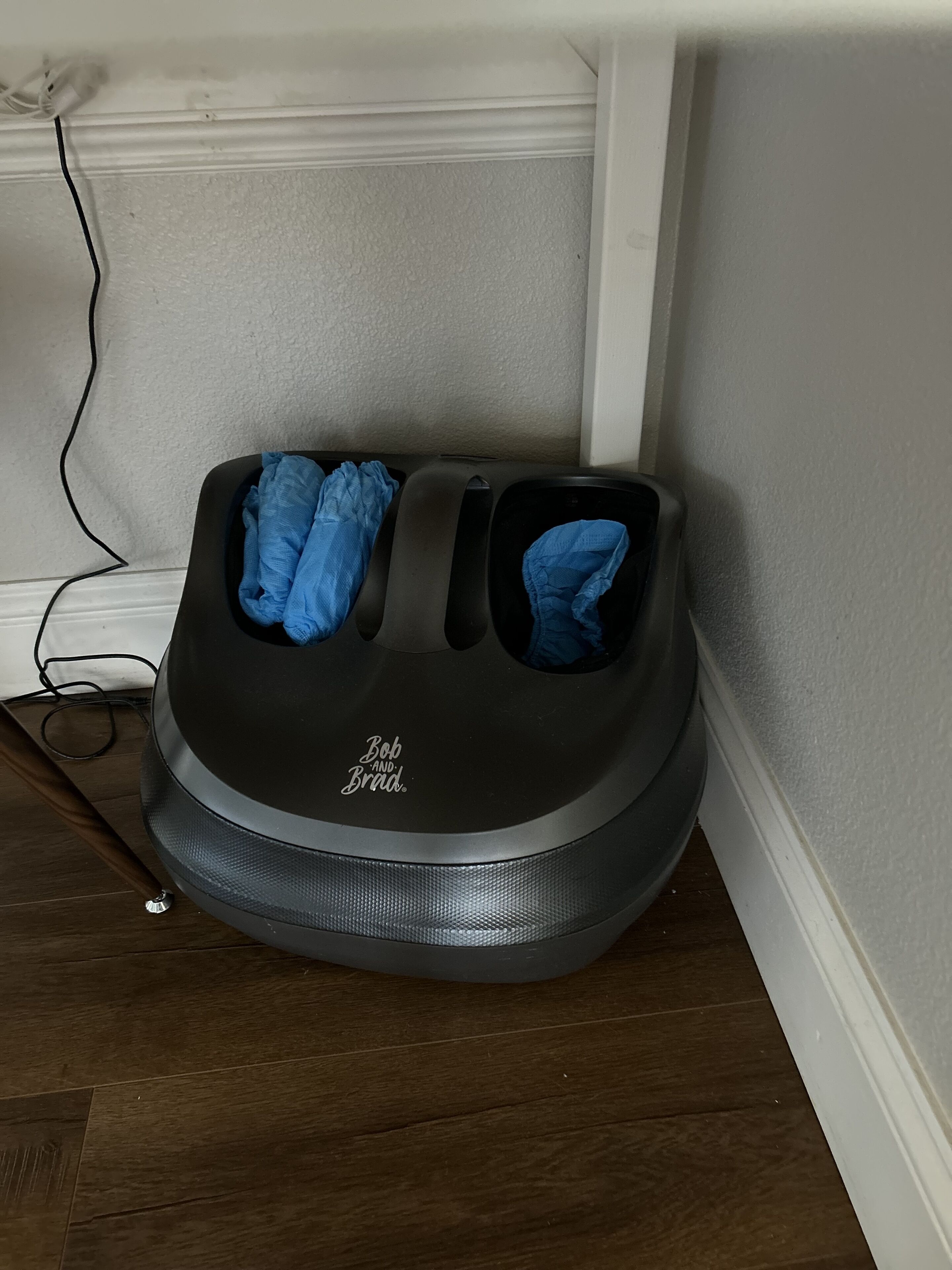 Una silla de masaje Bob and Brad ubicada en un rincón de una habitación con suelo de madera y paredes blancas.