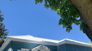 A two-story house with a blue exterior, white trim, and a front porch with a white railing. - Adorable, “ Beach View Cottage” Lake Michigan views! Best location!  (Ludington)