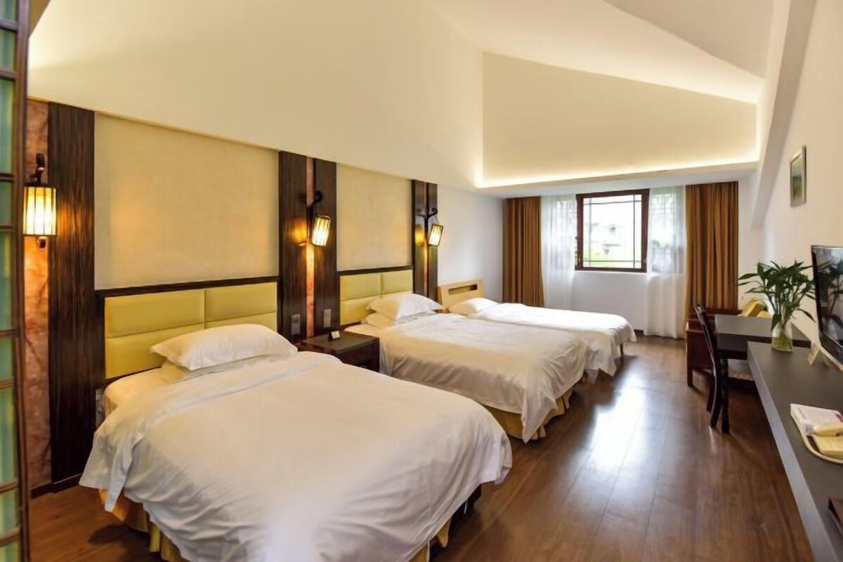 A hotel room with two beds, a desk, and a chair.
