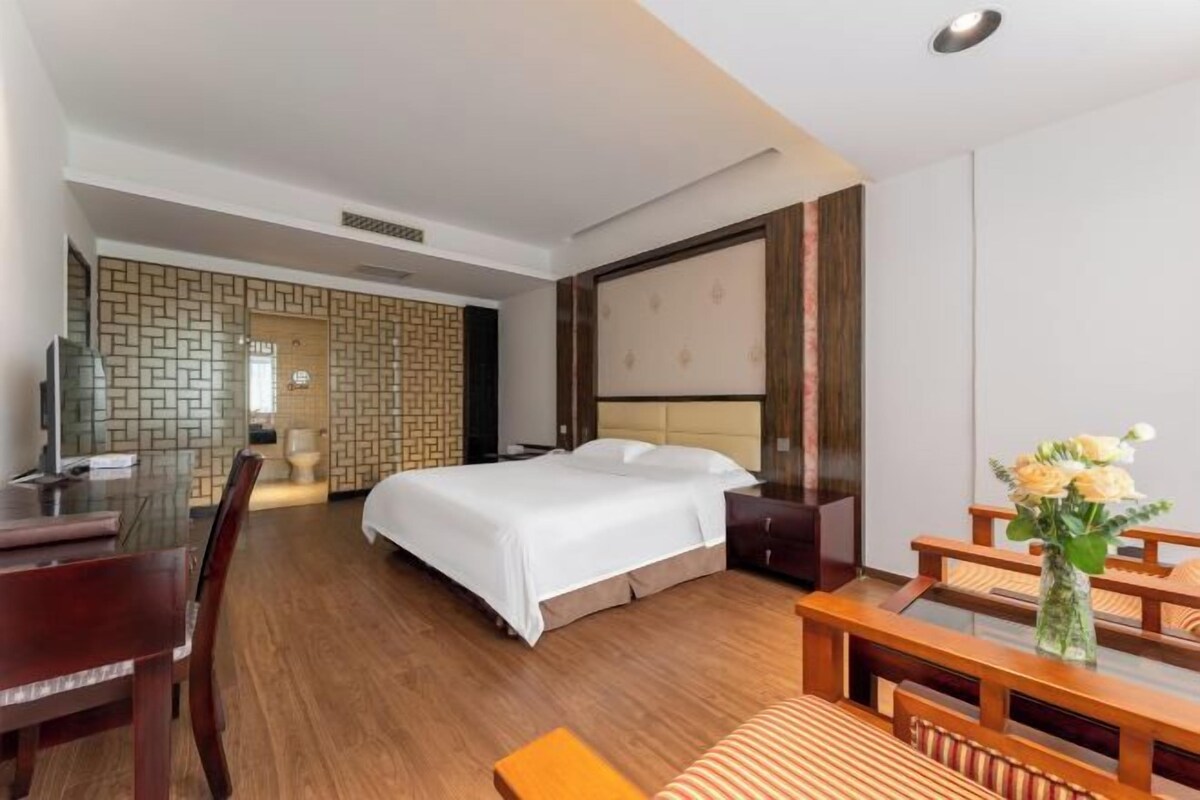 A hotel room with a bed, a desk, and a chair.