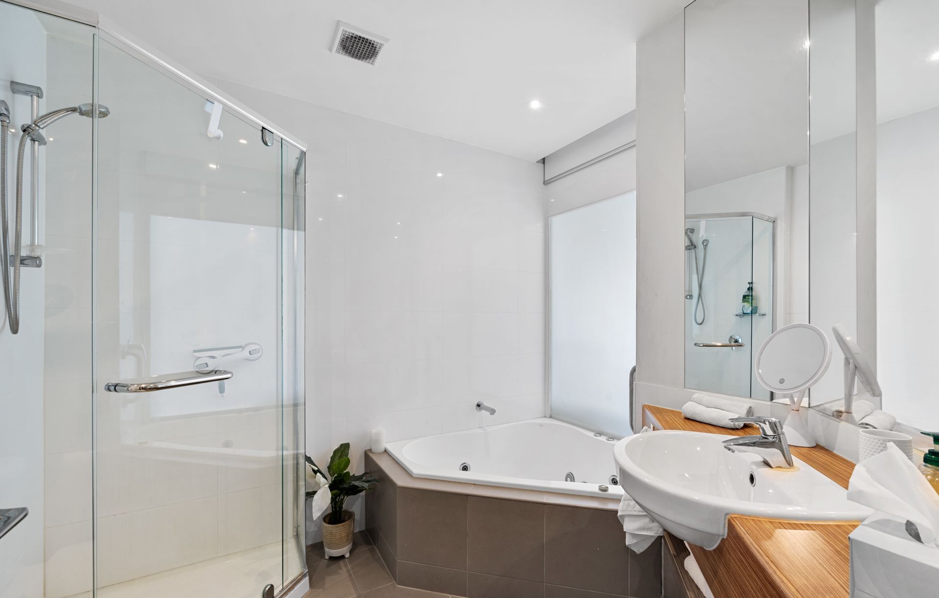 A modern bathroom with a glass-enclosed shower, a freestanding bathtub, and a vanity with a sink and mirror.