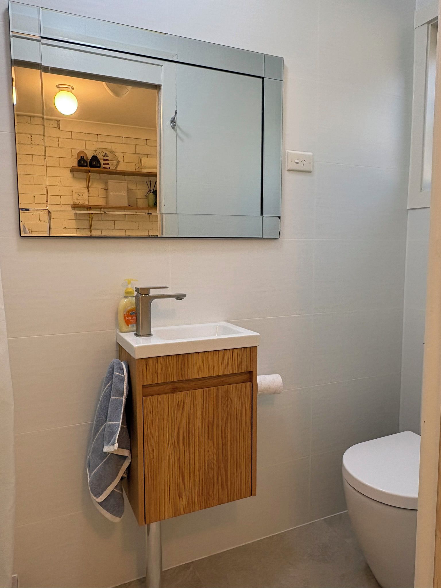 Ein Badezimmer mit einem Holzkabinent, einem weißen Waschbecken, einem Spiegel und einer Toilette.