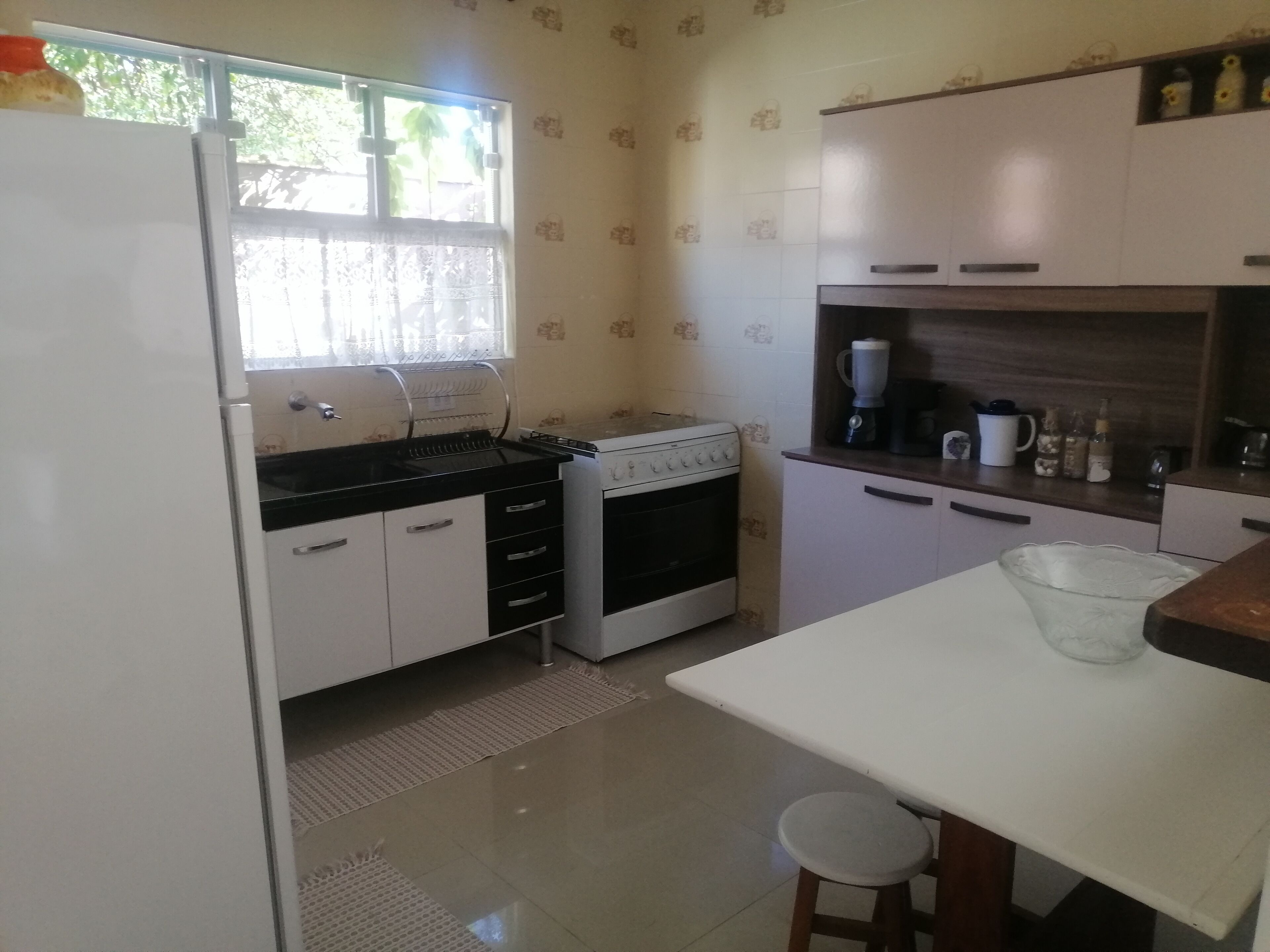 A compact kitchen with a refrigerator, stove, sink, and a small dining area.