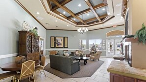 A spacious living room with a high ceiling, wooden beams, a dining area, and a fireplace. - Close to Disney, Seaworld, 4BR Townhouse with Hot Tub (Kissimmee)