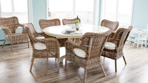 A dining area with wicker chairs and a round table, large windows, and a wooden floor. - Bayfront Home with Pier, Multi-Level Decks & Stunning LBI Views (Manahawkin)