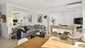 En moderne stue med en grå sofa, et træ sofabord og et spiseområde med et træbord.