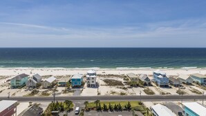 A coastal town with beachfront properties, a road, and a clear view of the ocean.