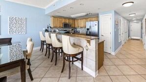 A modern kitchen with a central island, bar stools, and a dining table with chairs.