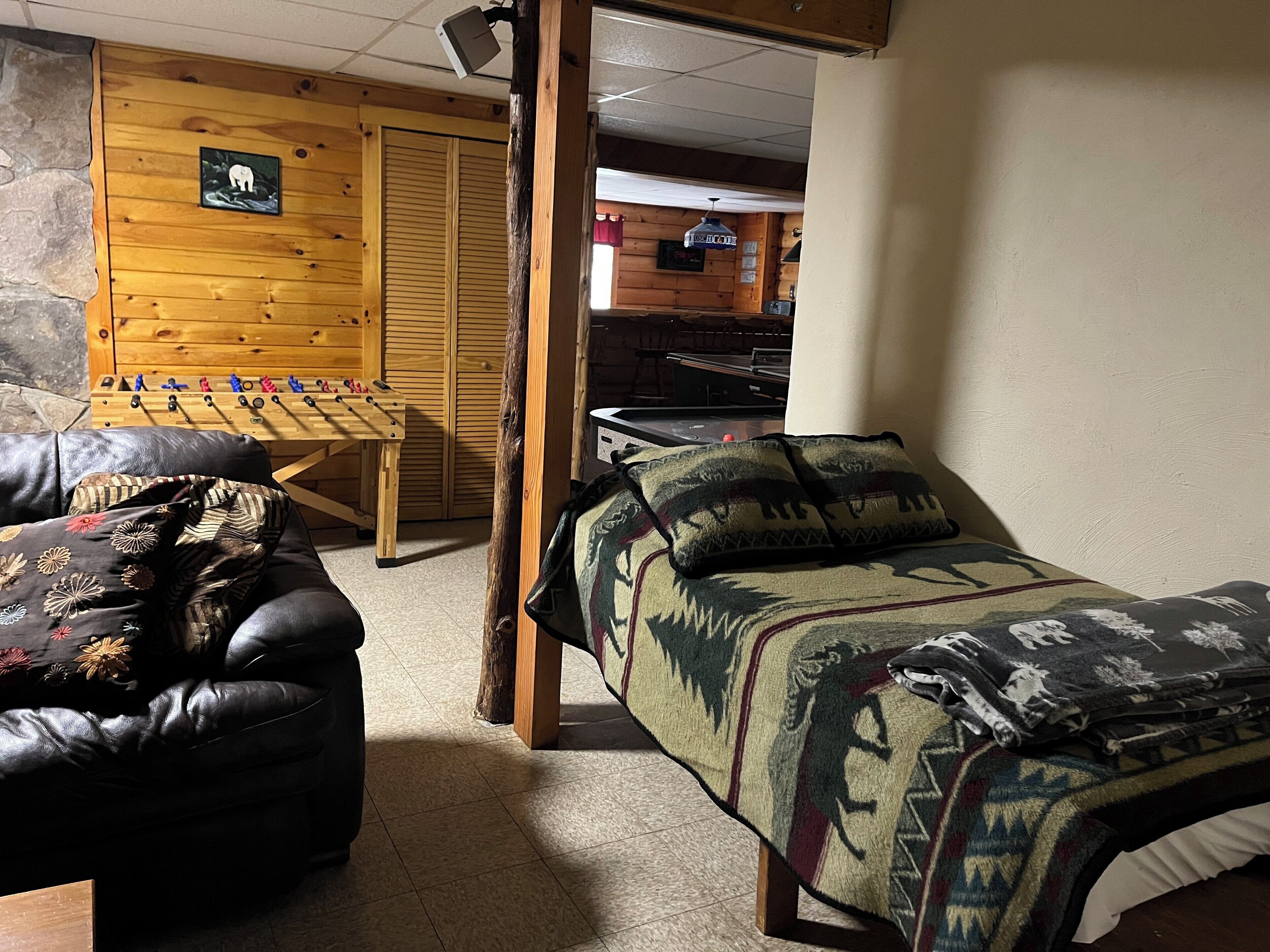 A cozy room with a bed, a sofa, and a foosball table.