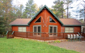 A log cabin with a porch, two windows, and a green roof.