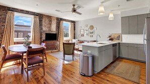 Una cocina moderna con armarios grises, una isla central y un comedor con mesa y sillas de madera.