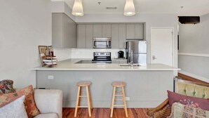 Una cocina moderna con una isla central, electrodomésticos de acero inoxidable y taburetes de bar.