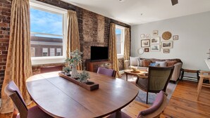 Una sala de estar con pared de ladrillo, chimenea, televisor y sofá.