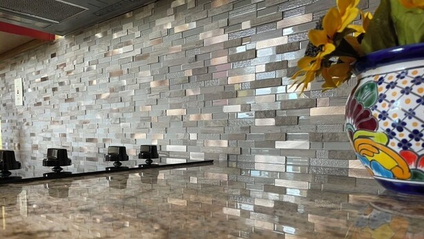 Una cucina con rivestimento a mosaico e un piano di lavoro in granito.