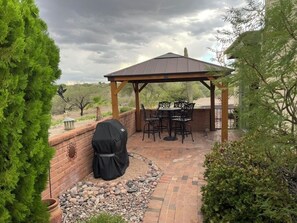 A covered patio area with a grill, outdoor seating, and a brick pathway. - AZ Desert Hills II Townhouse, Private with Stunning Mountain View! (Green Valley)