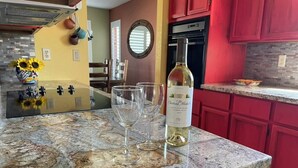 Una cucina con un piano di lavoro in granito, una bottiglia di vino e diversi bicchieri.