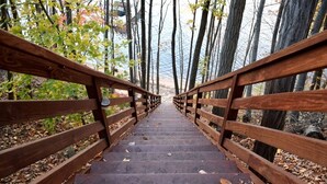A wooden staircase leading to a bridge over a body of water, surrounded by trees and fallen leaves. - Magnificent Riverfront home, completely private.  BOOK  7 NIGHTS GET 10% OFF (Middle Haddam)