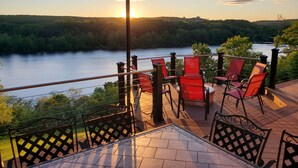 A terrace with red chairs and a table overlooking a river, with a sunset in the background. - Magnificent Riverfront home, completely private.  BOOK  7 NIGHTS GET 10% OFF (Middle Haddam)