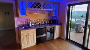 A modern kitchen with a bar area, featuring a wine cooler, a variety of bottles, and a glass display cabinet. - Magnificent Riverfront home, completely private.  BOOK  7 NIGHTS GET 10% OFF (Middle Haddam)