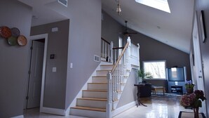 A spacious living room with a high ceiling, a staircase, and a large window providing natural light. - Magnificent Riverfront home, completely private.  BOOK  7 NIGHTS GET 10% OFF (Middle Haddam)