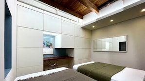 A bedroom with two beds, a desk, a mirror, and a wardrobe.