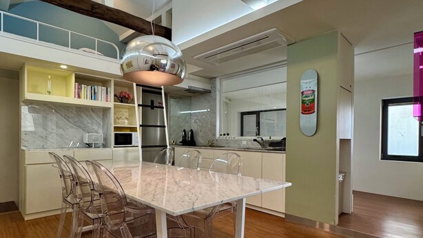 A modern kitchen with a marble countertop, a built-in microwave, and a stainless steel refrigerator.