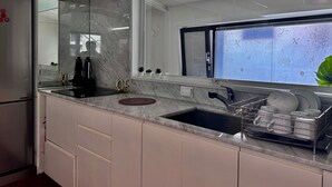 A modern kitchen with a built-in stove, a window with a decorative view, and a dish rack with plates.