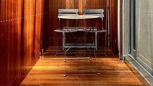 A narrow hallway with wooden walls and a wooden floor. There is a metal table with two chairs in the center.