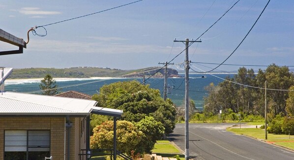 A coastal road with a view of the ocean and a bridge in the distance.