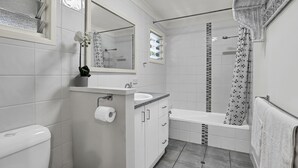 Une salle de bain moderne équipée d’un WC, d’un lavabo, d’un miroir, d’une douche et d’un porte-serviettes.