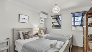 Une chambre avec deux lits, un luminaire au plafond et une fenêtre donnant sur l’extérieur.
