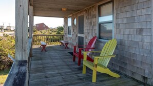 A wooden deck with Adirondack chairs and a picnic table.
