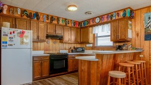 A kitchen with wooden cabinets, a refrigerator, a stove, and bar stools.
