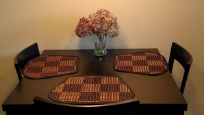 Une table à manger ornée d’un vase de fleurs, quatre chaises et un lustre.