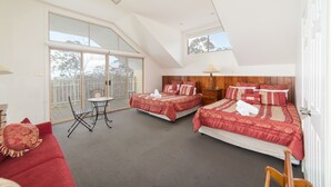 A bedroom with two beds, a ceiling fan, and a balcony with a view of trees.
