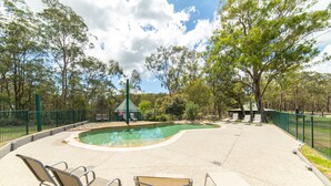 A pool area with lounge chairs and a small building in the background.