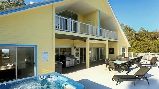 A two-story building with a hot tub and outdoor seating area.
