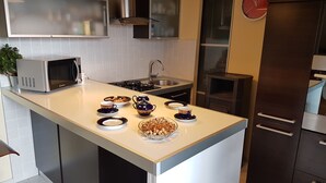 Een moderne keuken met een centraal eiland, roestvrijstalen apparatuur en een klok aan de muur.
