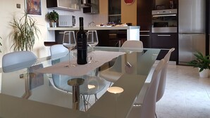 Een moderne keuken met roestvrijstalen apparatuur, een eethoek met een glazen tafel en een klok aan de muur.