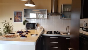 Een moderne keuken met een magnetron, gasfornuis en roestvrijstalen apparatuur. Op het aanrecht staan decoratieve schalen en potten.