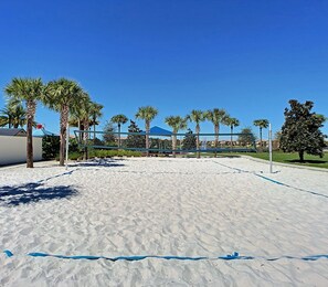 Enjoy a game of volleyball on the sandy court surrounded by lush palm and other trees.