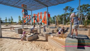 Une aire de jeux avec des bacs à sable, un toboggan et des structures colorées.