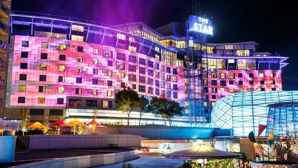 Un hôtel à plusieurs étages, reconnaissable à son grand panneau lumineux représentant une « ÉTOILE », et doté d’une architecture moderne qui allie verre et métal.