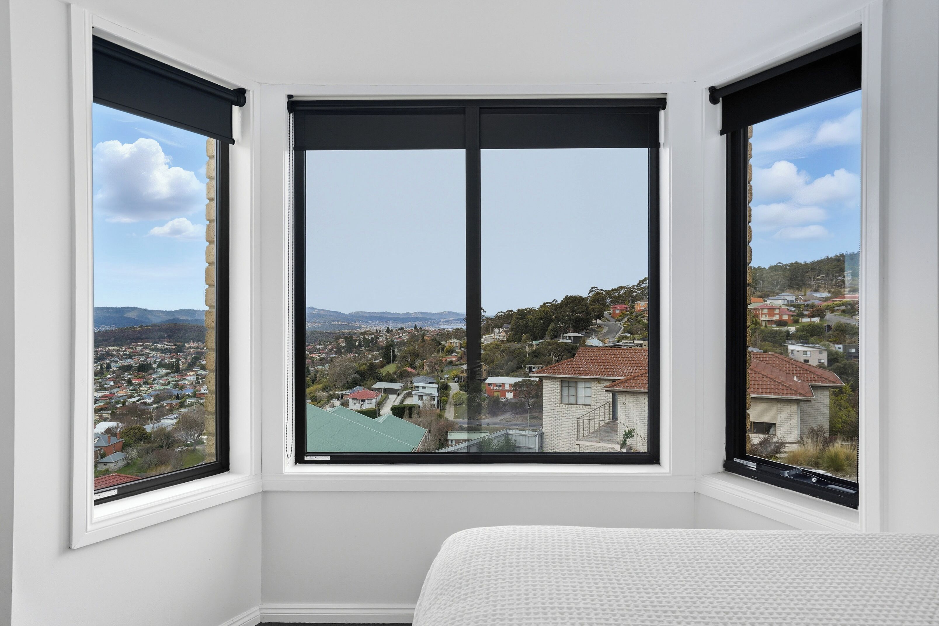 A room with a large window offering a view of a residential area with houses and hills.