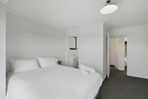 A hotel room with a large bed, a bedside table, a mirror, and a door leading to a bathroom. - Large house, centrally located with amazing views  (Lenah Valley)